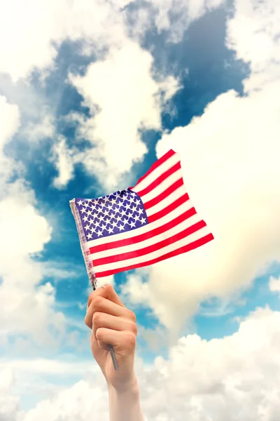 Imagen compuesta de la mano ondeando bandera americana — Foto de Stock