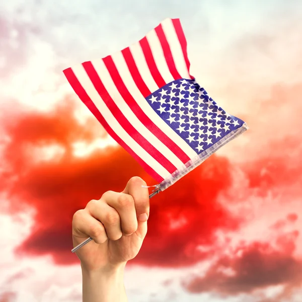 Imagen compuesta de la mano ondeando bandera americana — Foto de Stock