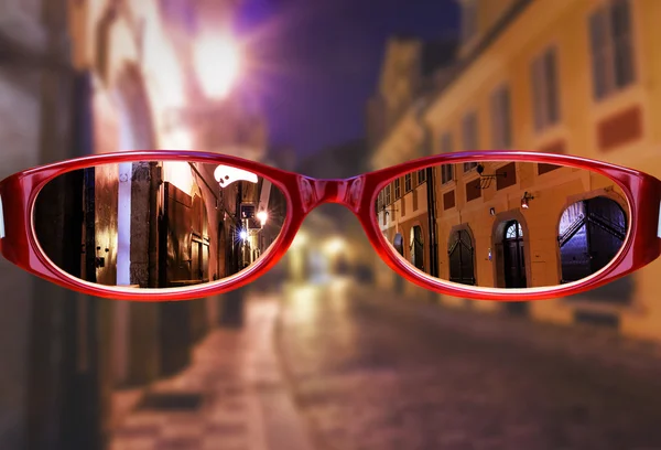 Glazen tegen stad bij nacht — Stockfoto