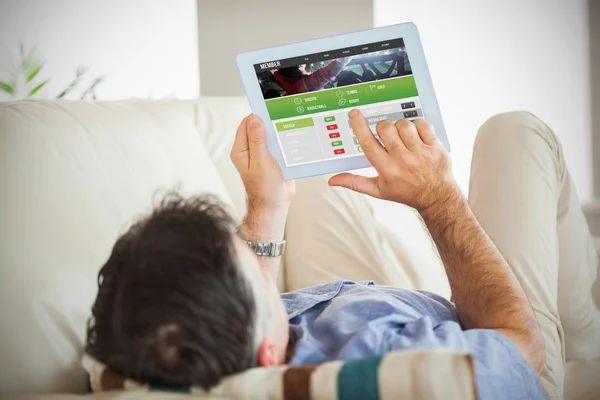 Man laying on sofa using a tablet pc — Stock Photo, Image