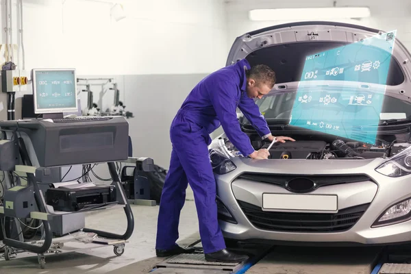 Mechanic leaning on a car looking at the engine — Stock Photo, Image