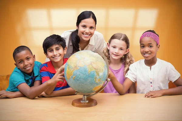 Leerlingen en leraar kijken naar globe in bibliotheek — Stockfoto