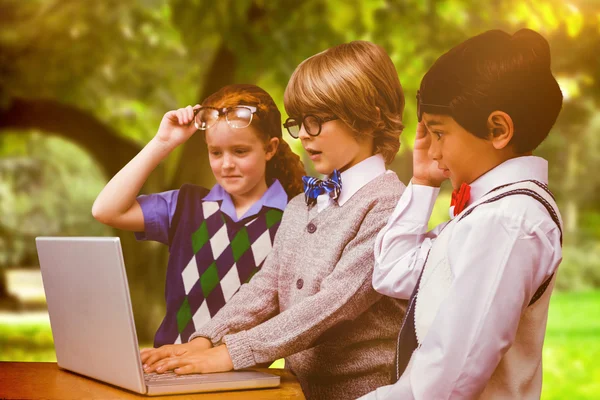 Leerlingen met behulp van laptop tegen bomen — Stockfoto