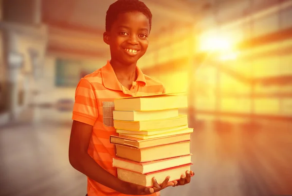 Menino bonito carregando livros na biblioteca — Fotografia de Stock