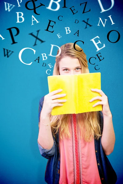 Estudiante cubriendo la cara con libro en biblioteca —  Fotos de Stock