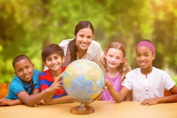 Pupils and teacher looking at globe — Stock Photo, Image