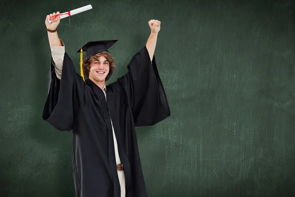 Studente maschio in vestaglia laureato alzando le braccia — Foto Stock