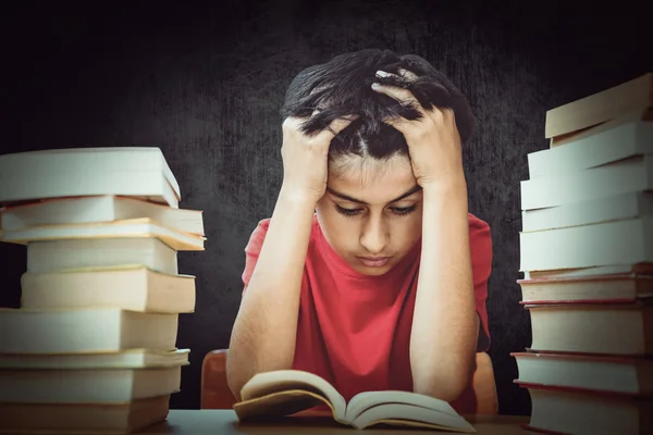 Gespannen jongen zitten met stapel boeken — Stockfoto