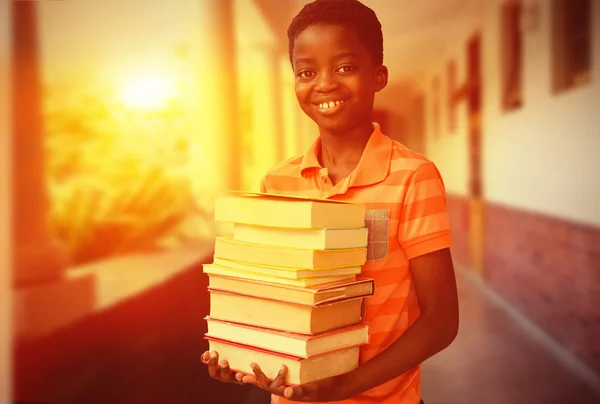 Carino ragazzo portando libri in biblioteca — Foto Stock