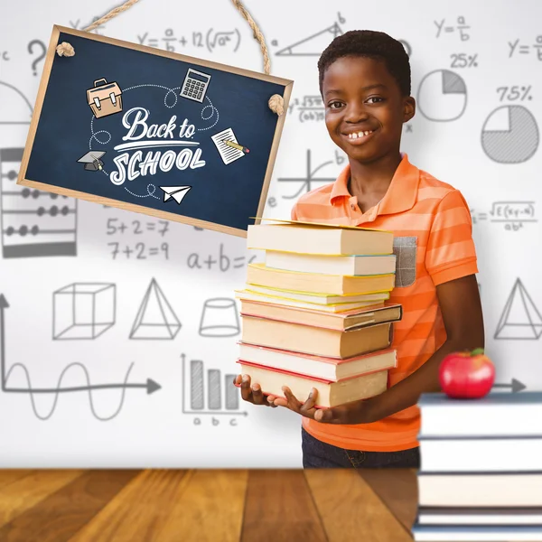 Imagen compuesta de retrato de un chico lindo llevando libros en la biblioteca — Foto de Stock