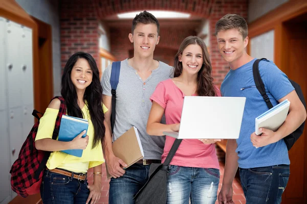 Grupo sonriente de estudiantes sosteniendo una computadora portátil — Foto de Stock