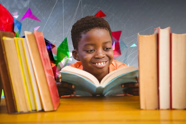 Мальчик читает книгу в библиотеке — стоковое фото