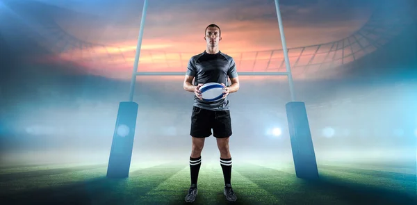 Jugador de rugby serio en camiseta negra sosteniendo la pelota — Foto de Stock