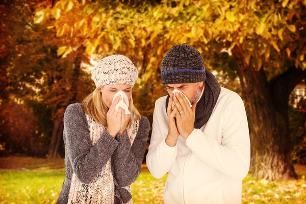 Composite image of couple sneezing in tissue — Stock Photo, Image