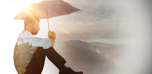 Geschäftsmann sitzt mit schwarzem Regenschirm auf dem Boden — Stockfoto