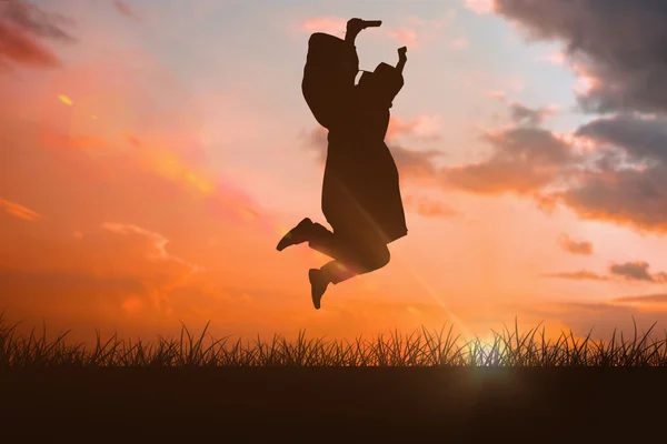 Happy male student in graduate robe jumping — Stock Photo, Image