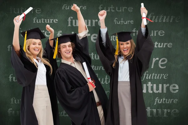 Três estudantes em roupão de pós-graduação levantando seus — Fotografia de Stock