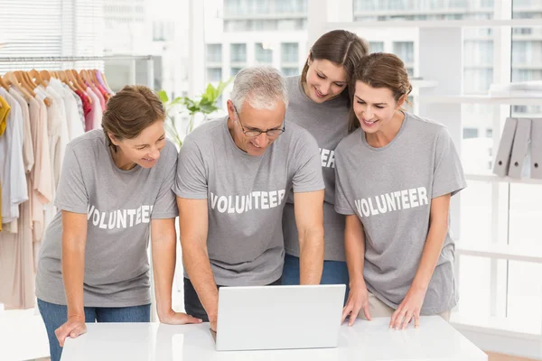 Leende volontärer med laptop tillsammans — Stockfoto