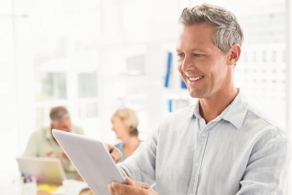 Empresário sorridente rolando em um tablet — Fotografia de Stock