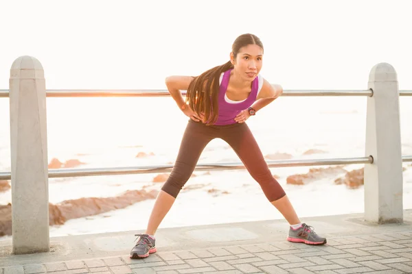 Vältränad kvinna stretching vid strandpromenaden — Stockfoto