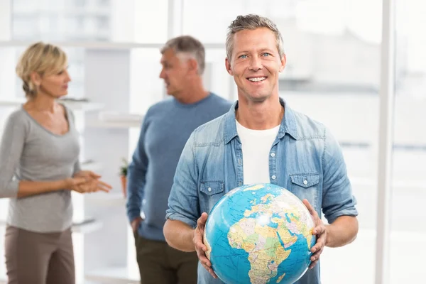 Empresário sorridente segurando globo terrestre — Fotografia de Stock
