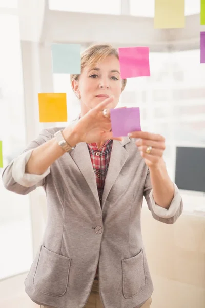 Mujer de negocios poniendo notas adhesivas o — Foto de Stock