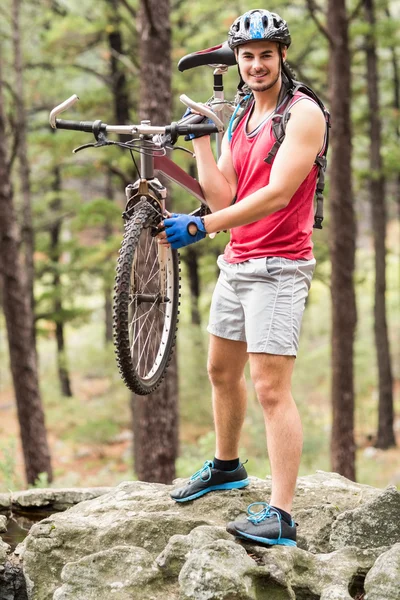 Motociclista segurando bicicleta em uma rocha — Fotografia de Stock