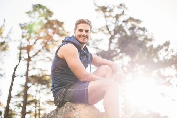 Young happy jogger sitting on rock — Stock Photo, Image