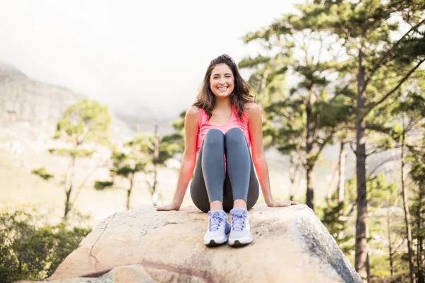 Glückliche Joggerin sitzt auf Felsen — Stockfoto