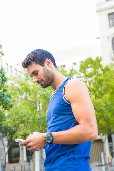 Atleta bonito usando smartphone — Fotografia de Stock