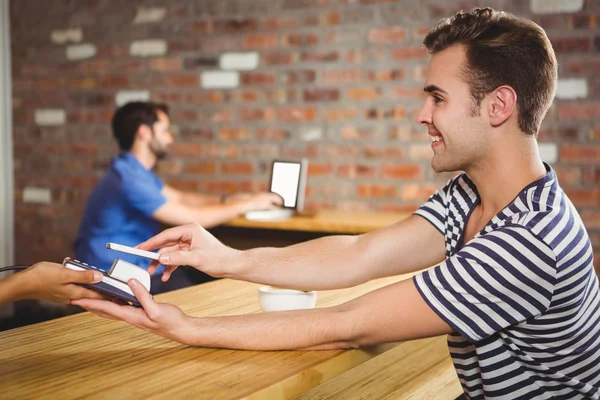 Mann bezahlt mit seinem Smartphone ein Croissant und einen Kaffee — Stockfoto