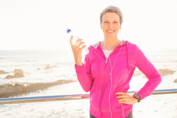 Woman with headphones holding bottle — Stock Photo, Image