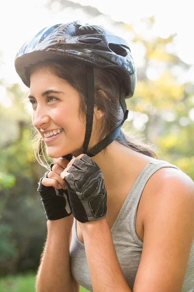 Athletic brunette putting on helmet — Stock Photo, Image