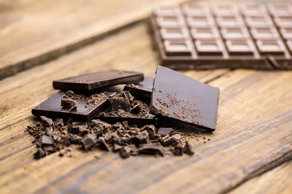 Pedaços de chocolate em uma mesa de madeira — Fotografia de Stock