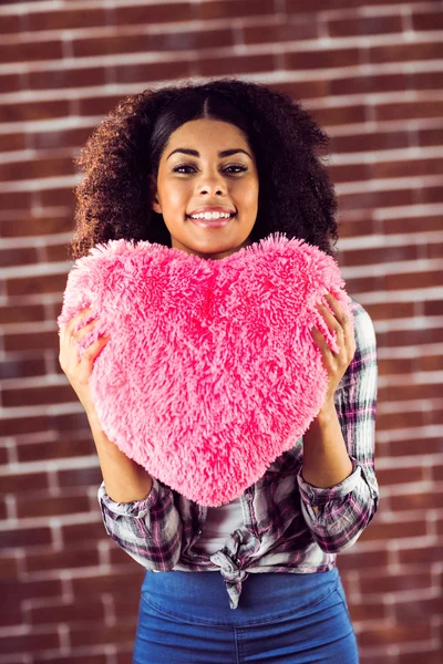 Woman holding up heart-shaped pillow — Stock Photo, Image