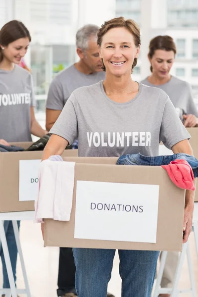 Mujer sonriente voluntaria llevando caja de donaciones — Foto de Stock