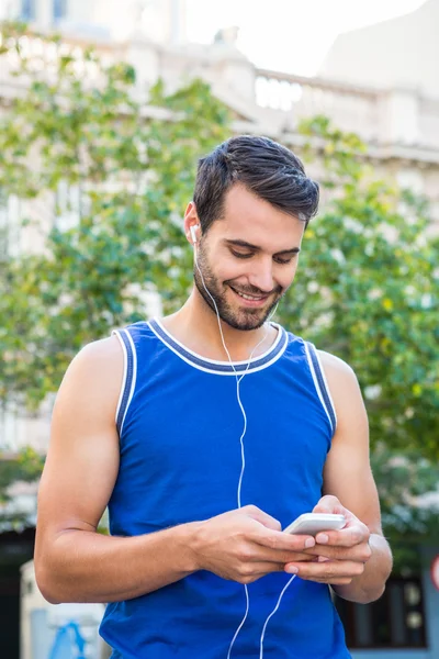 Atleet glimlachend en gebruikend smartphone — Stockfoto