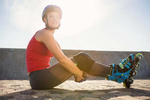 Gülümseyen sportif sarışın patenci oturan — Stok fotoğraf