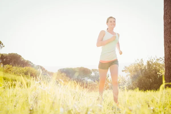 Athlète blonde jogging dans l'herbe — Photo