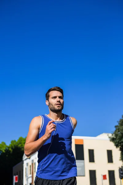 Athlete jogging against blue sky — Stock Photo, Image