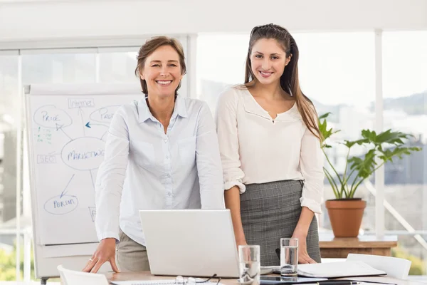 Lachende vrouwelijke ondernemers met behulp van laptop — Stockfoto