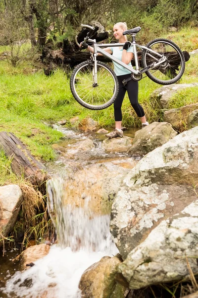 Женщина, поднимающая велосипед — стоковое фото