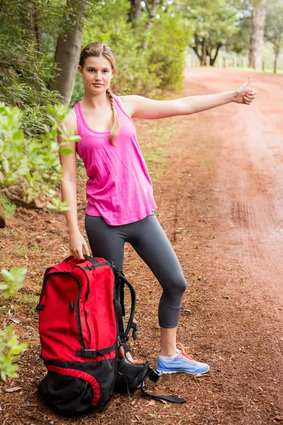 Blonde with backpack hitchhiking — Stock Photo, Image