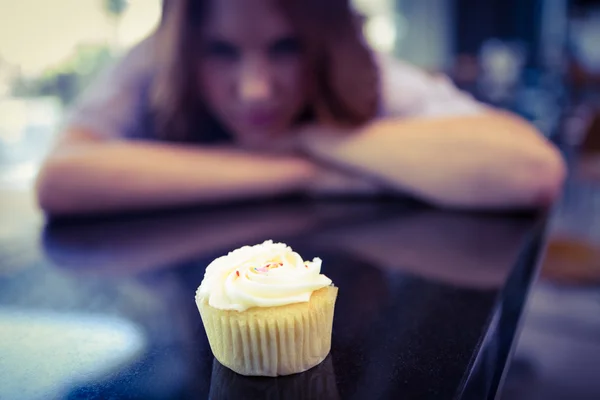 Bella bruna guardando cupcake — Foto Stock