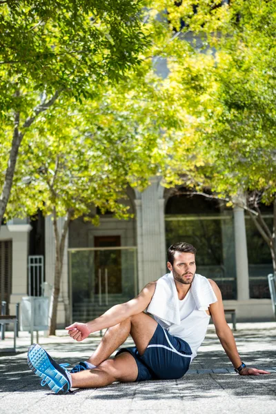 Han sportovec s ručníkem protahování nohou — Stock fotografie