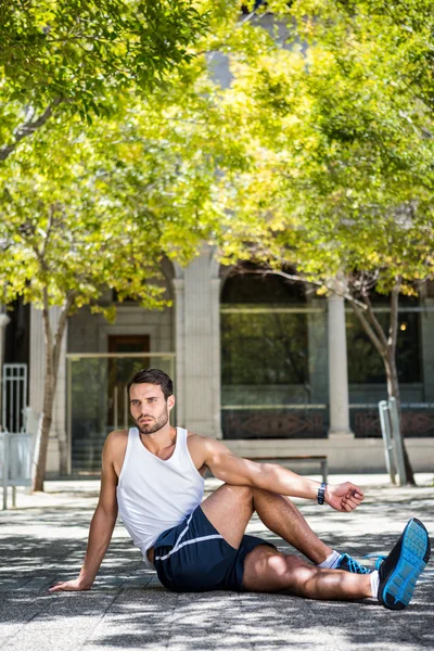 Knappe atleet, die zich uitstrekt zijn been — Stockfoto