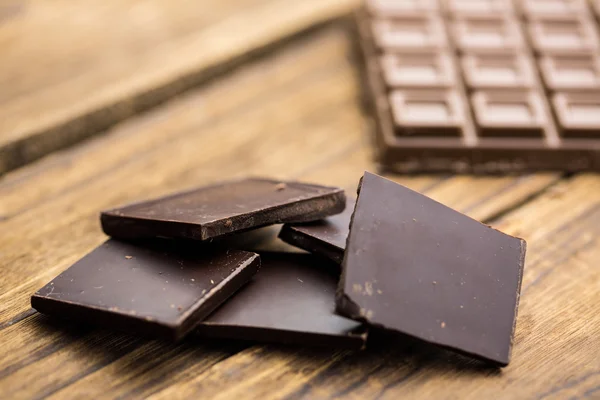 Stukken van chocolade op een houten tafel — Stockfoto