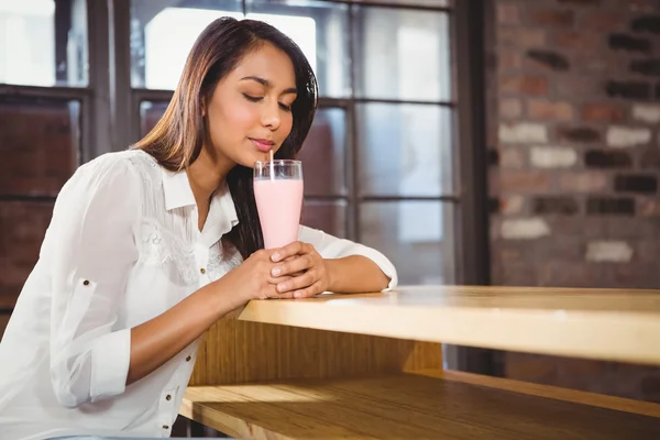 Vrouw drinken een roze milkshake — Stockfoto