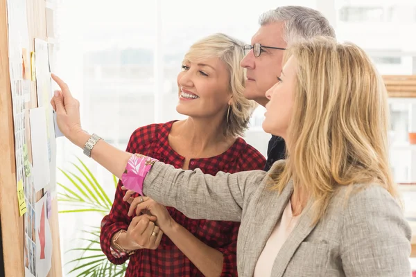Smiling business team pointing a note — Stock Photo, Image