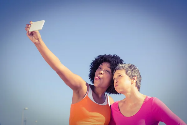 Duas mulheres desportivas posando e tirando selfie — Fotografia de Stock